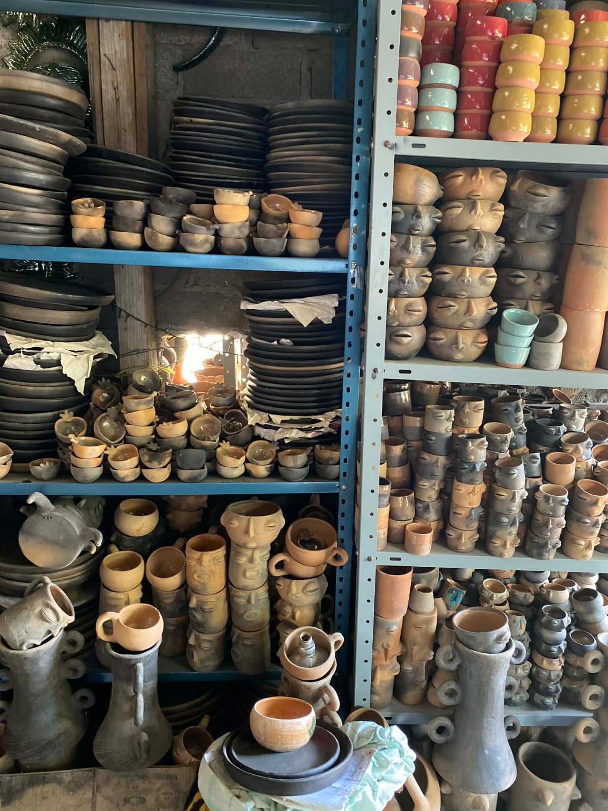 Shelves of handmade Oaxacan clay ceramics: black clay plates, face pottery, cups